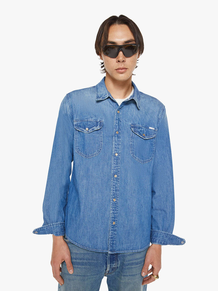 Front view of a man in a vintage blue button-up with front patch pockets and a slightly curved hem.