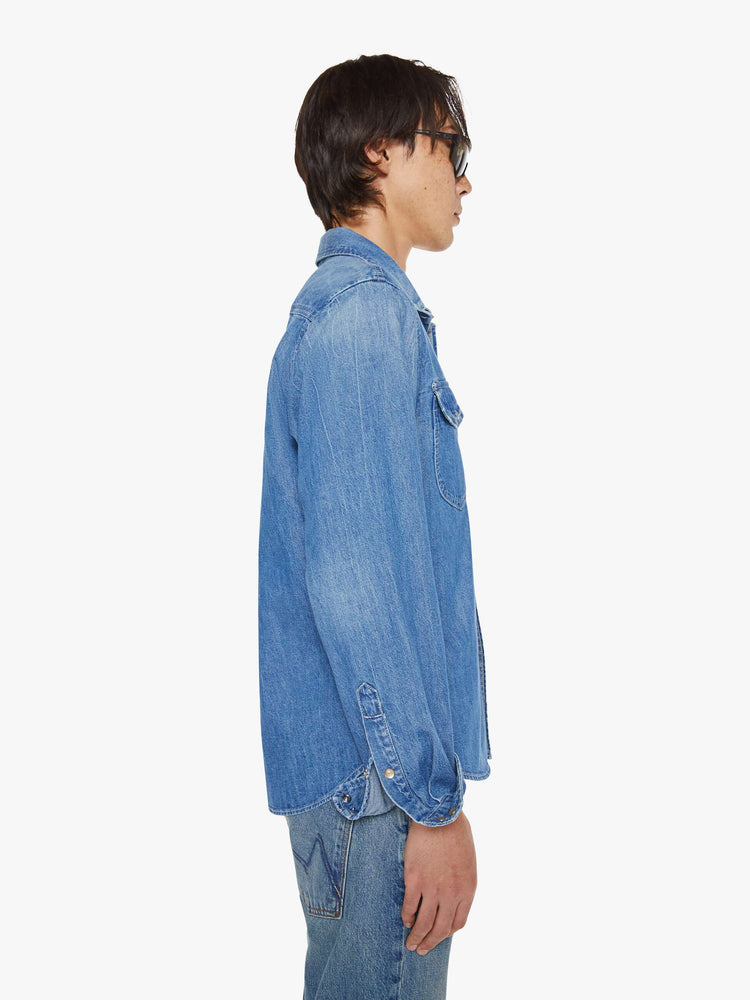 Side view of a man in a vintage blue button-up with front patch pockets and a slightly curved hem.