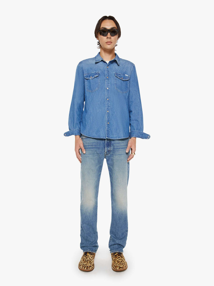 Full body view of a man in a vintage blue button-up with front patch pockets and a slightly curved hem.