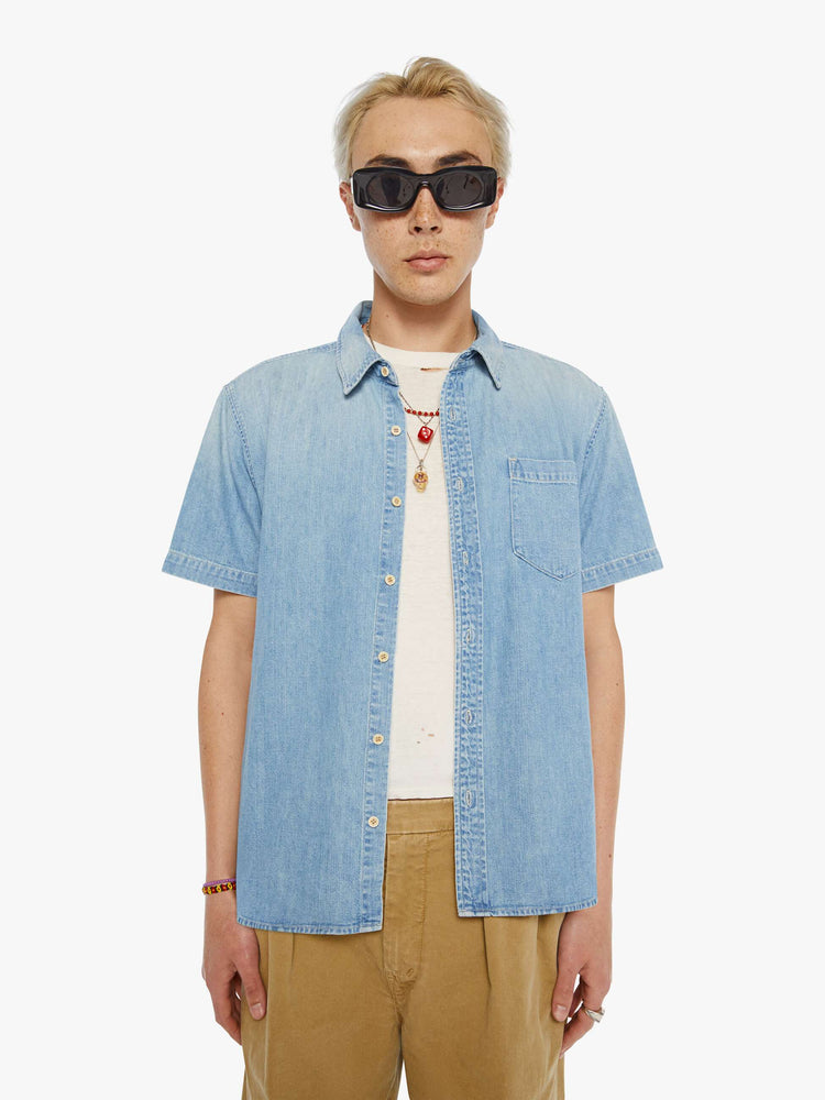 Front view of a man in a light blue short-sleeve collared button-up with a patch pocket and a straight hem.