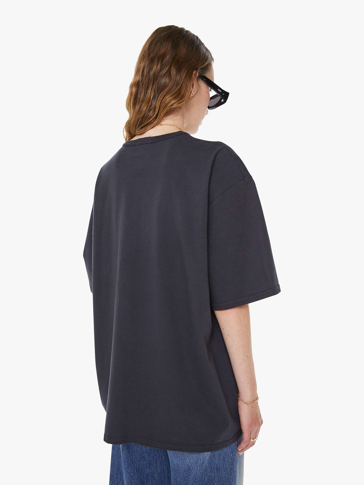 WOMAN Back view faded black tee features an oversized yellow text graphic on the front.
