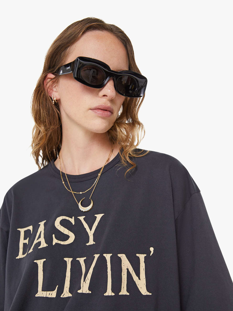 WOMAN close up view faded black tee features an oversized yellow text graphic on the front.