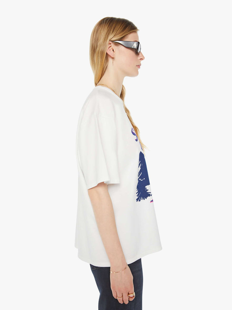 WOMAN side view in an oversized tee in white with hand-drawn graphic in blue and pink on the front inspired by a camp counselor tee.