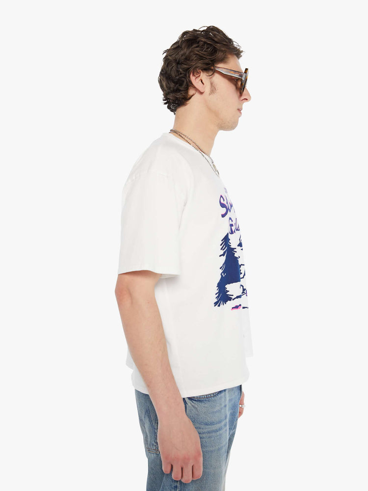 MEN side view in an oversized tee in white with hand-drawn graphic in blue and pink on the front inspired by a camp counselor tee.