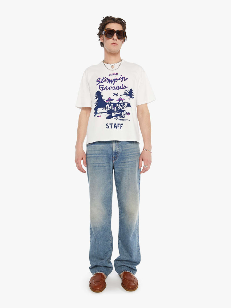 MEN full body view in an oversized tee in white with hand-drawn graphic in blue and pink on the front inspired by a camp counselor tee.