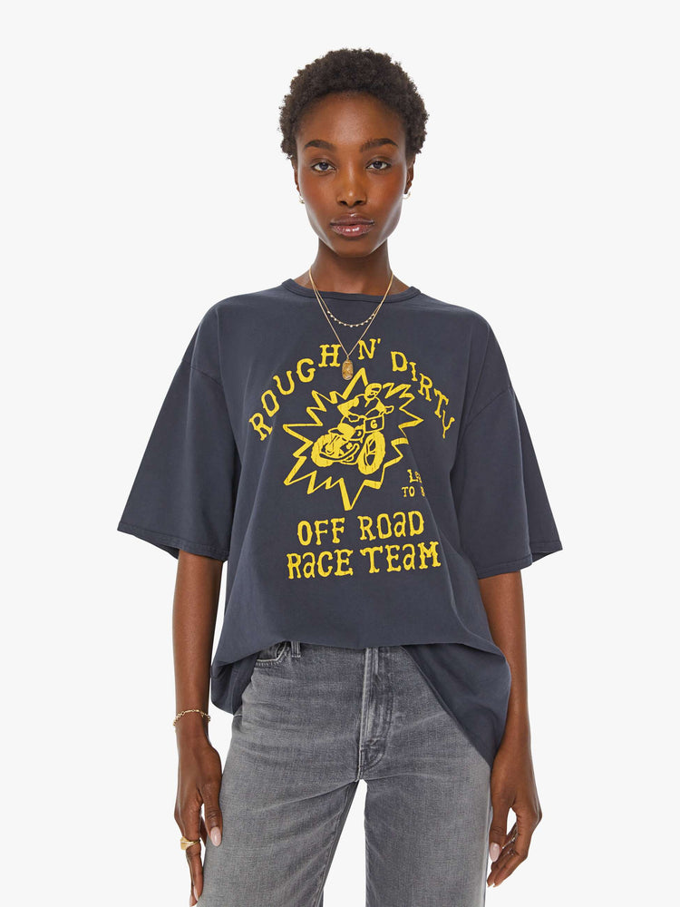 WOMAN front view in a faded black tee with a yellow graphic on the front inspired by a dirt bike racing team.
