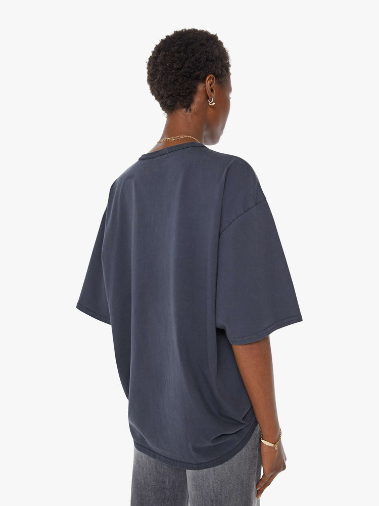 WOMAN back view in a faded black tee with a yellow graphic on the front inspired by a dirt bike racing team.