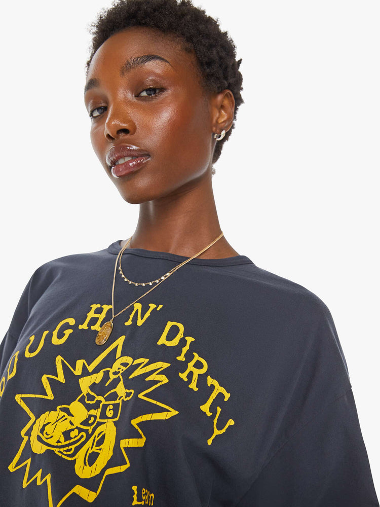 WOMAN close up view in a faded black tee with a yellow graphic on the front inspired by a dirt bike racing team.