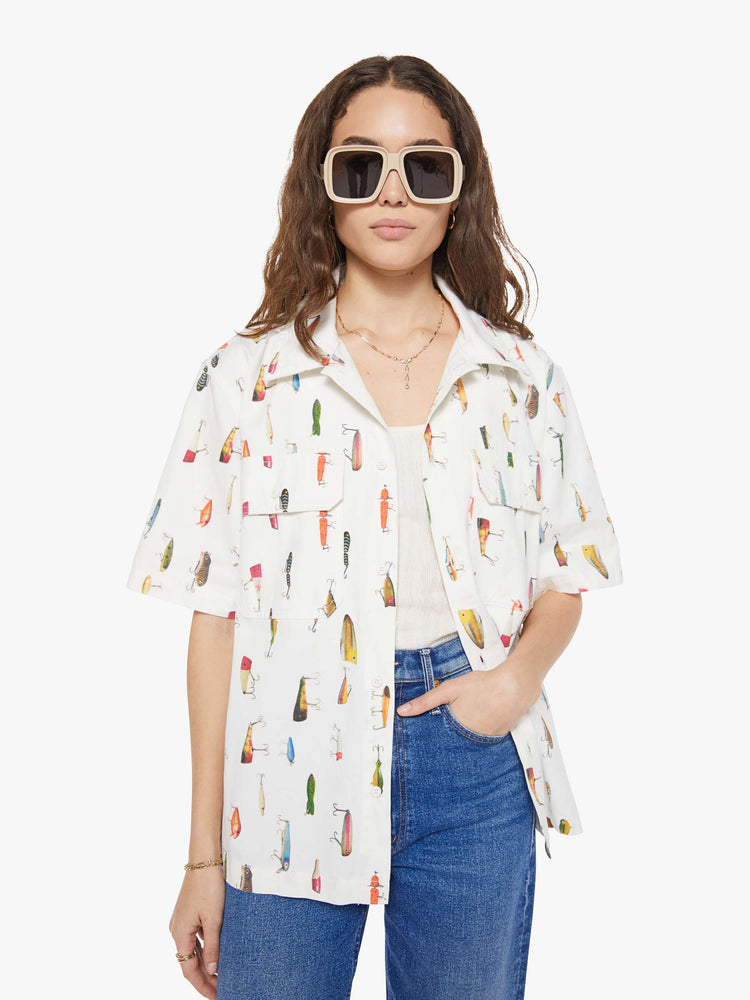 WOMAN front view of a bright white with a colorful fishing lure print short-sleeve button-up with front patch pockets and a boxy fit. 