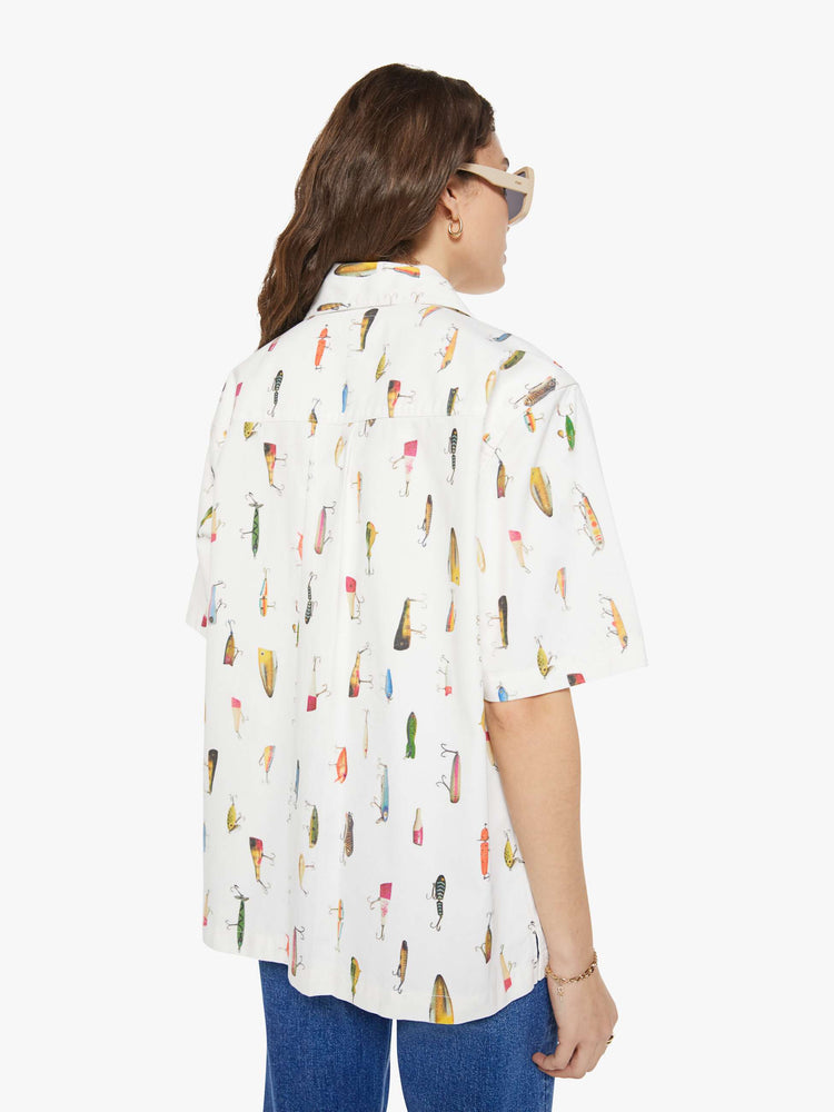 WOMAN back view of a bright white with a colorful fishing lure print short-sleeve button-up with front patch pockets and a boxy fit. 
