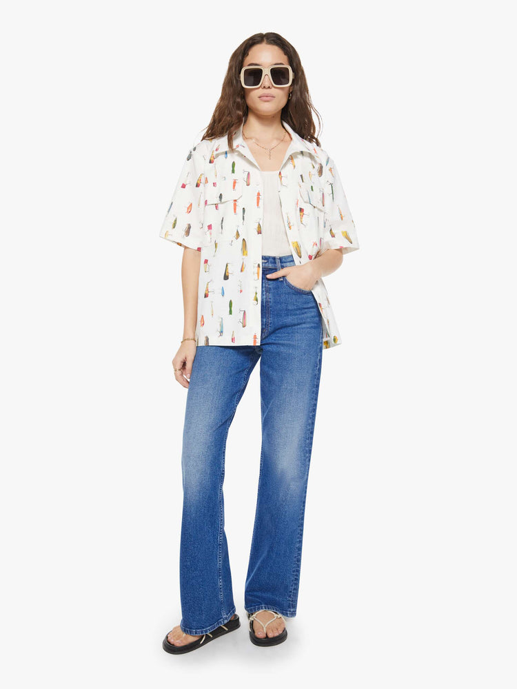 WOMAN full body view of a bright white with a colorful fishing lure print short-sleeve button-up with front patch pockets and a boxy fit. 