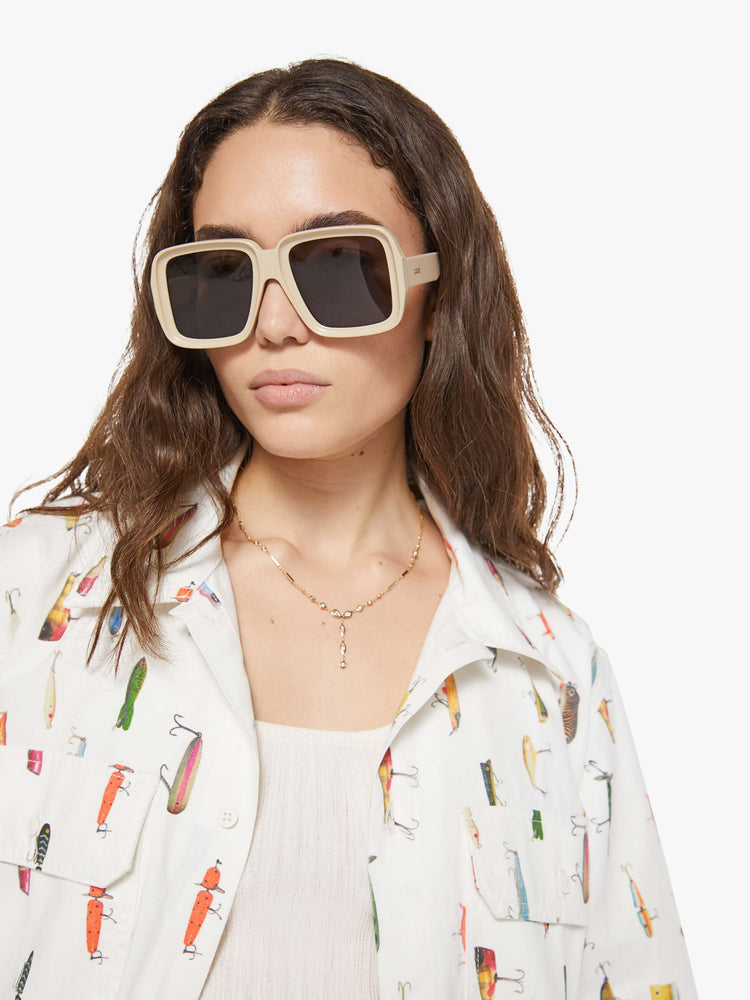 WOMAN close up view of a bright white with a colorful fishing lure print short-sleeve button-up with front patch pockets and a boxy fit. 