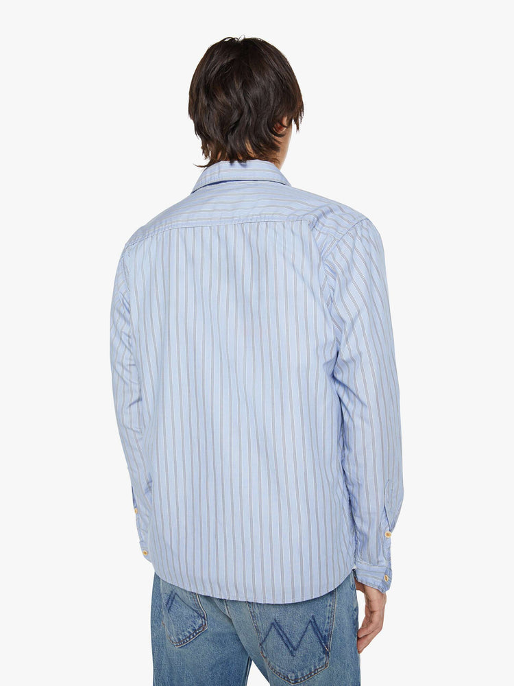 Back view of a man in a light blue, black and white stripe classic button-up with a loose fit and slightly cropped hem.