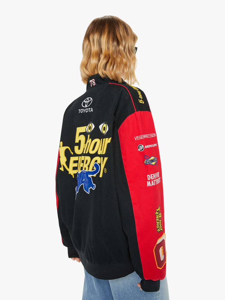 Back image of a woman wearing a racer jacket in black and red featuring various patches.