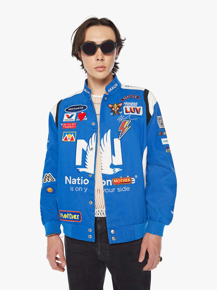 Front image of a mens blue racer jacket featuring assorted patches.