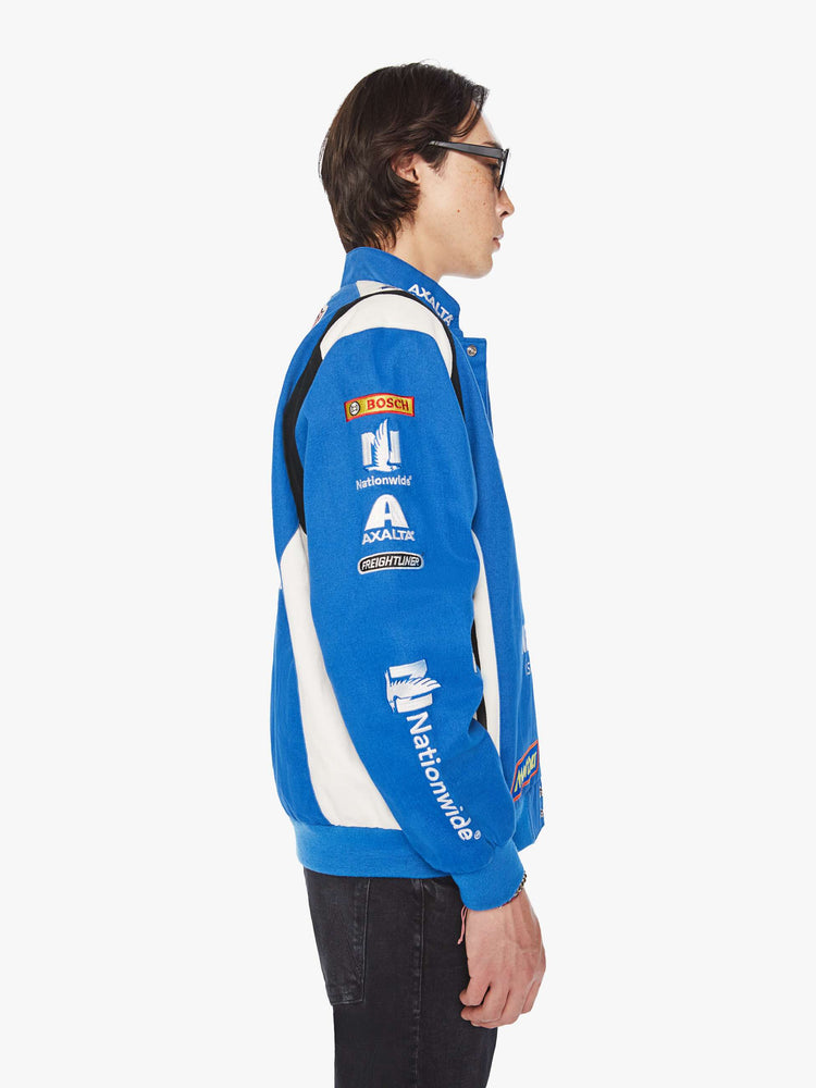 Side image of a mens blue racer jacket featuring assorted patches.