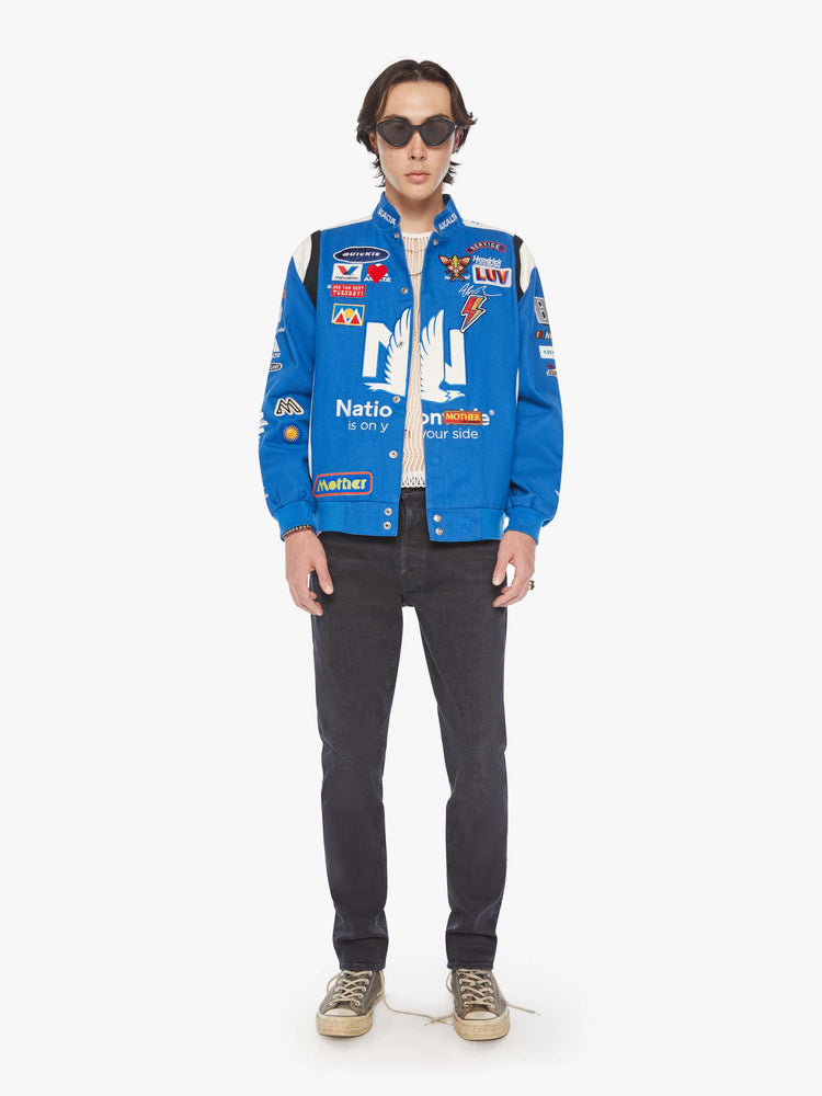 Front view of a mens image of a racer jacket in blue with assorted patches.