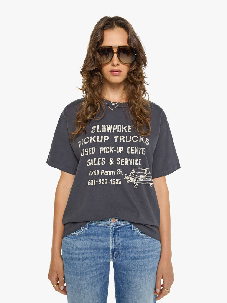 WOMAN front view in a dark grey oversized tee features a crackled text graphic and pickup truck in white on the front.