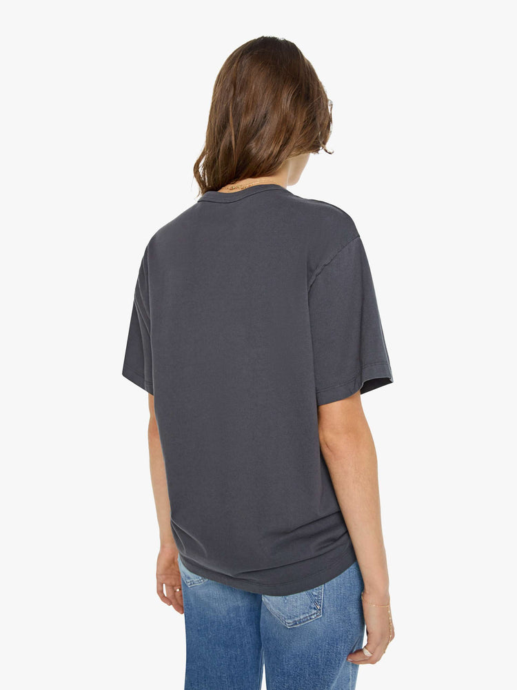 WOMAN back view in a dark grey oversized tee features a crackled text graphic and pickup truck in white on the front.