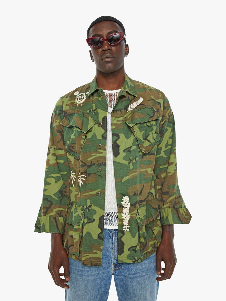 Front view of a mens camo jacket featuring front patch pockets and white embroidery details.