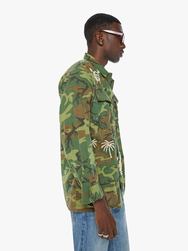Side view of a mens camo jacket featuring front patch pockets and white embroidery details.