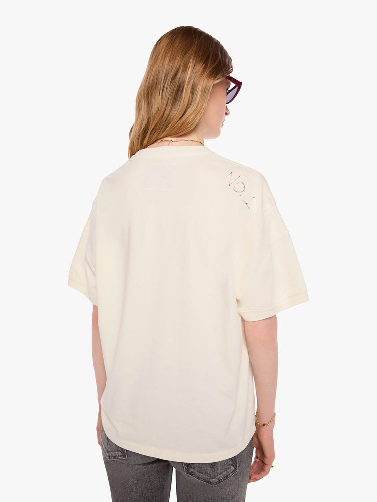 WOMAN back view of an off-white tee with a faded, vintage-inspired green football graphic with text on the front.