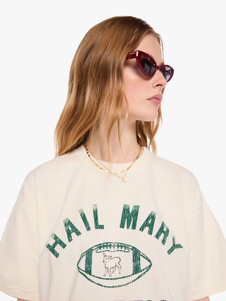 WOMAN close up view of an off-white tee with a faded, vintage-inspired green football graphic with text on the front.