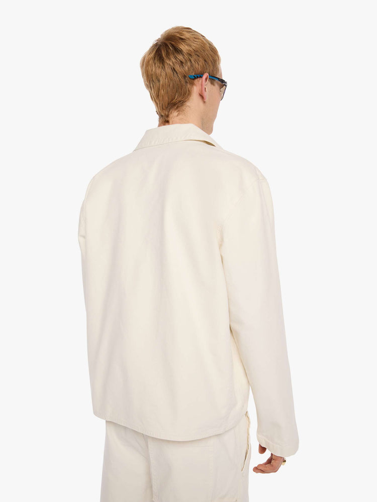 Back view of a man in a jacket designed in cream with tonal buttons down the front.