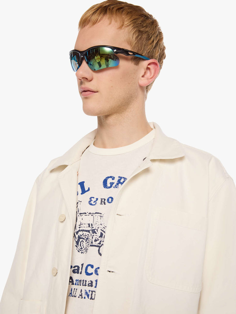 Close up view of a man in a jacket designed in cream with tonal buttons down the front.