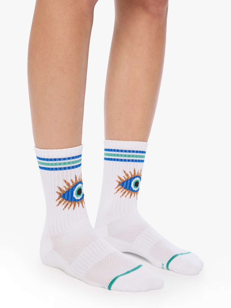 On model side view of tube socks designed in white with a blue eye on the front and stripe detailing.