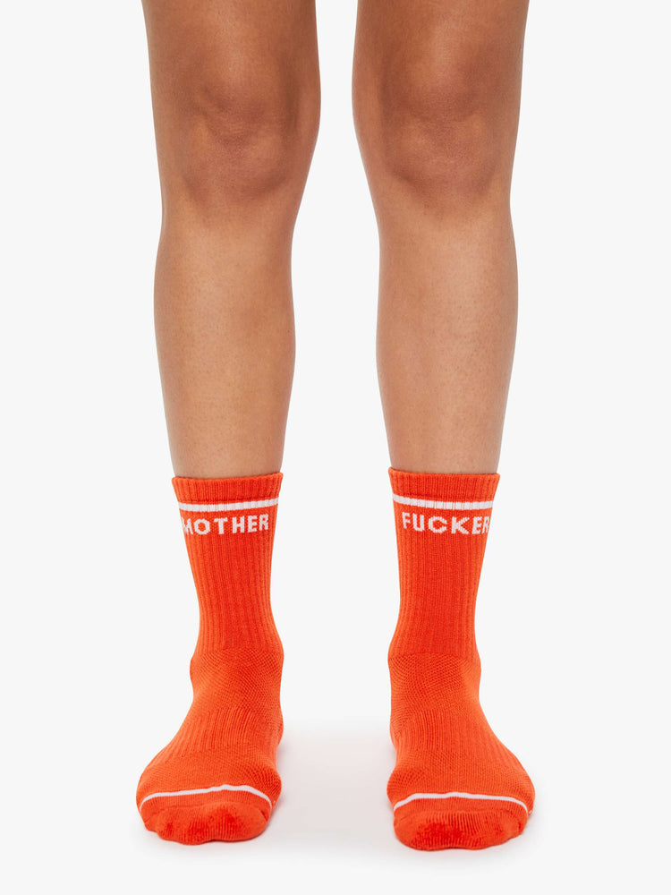On model view of a vintage-inspired tube socks in bright orange and bold lettering in white.