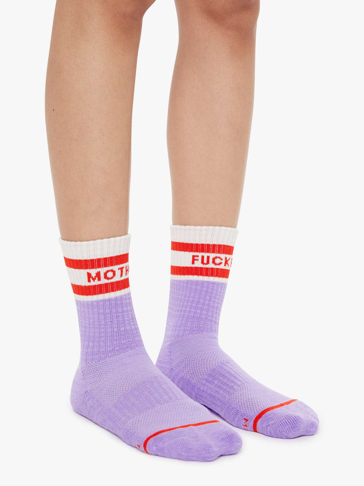 Side view of lavender and white with red lettering details socks on a model feet.