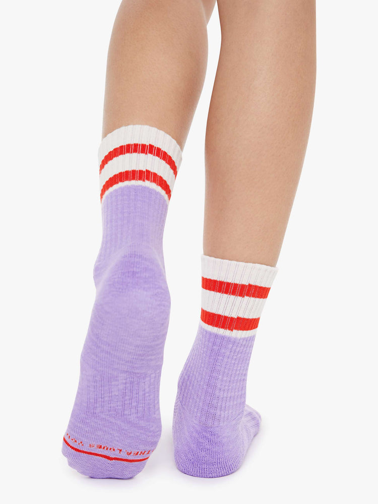 Back view of lavender and white with red lettering details socks on a model feet.