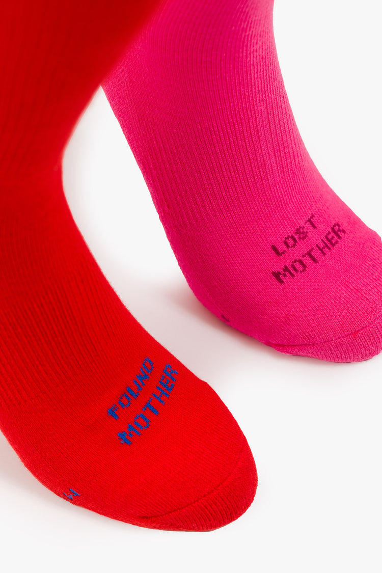 Close up view of retro tube socks in shades of pink and red with burgundy and blue stripes and text on the feet.