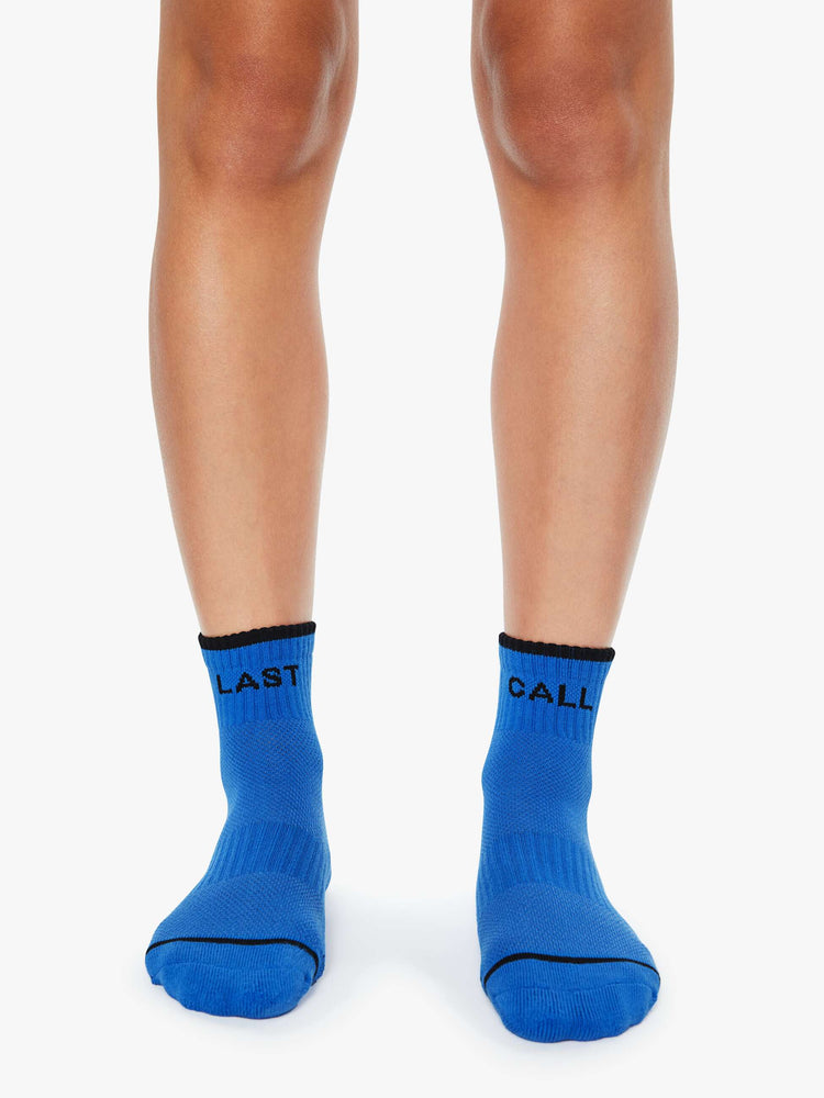 On model ankle-length tube socks in blue with black text and details.