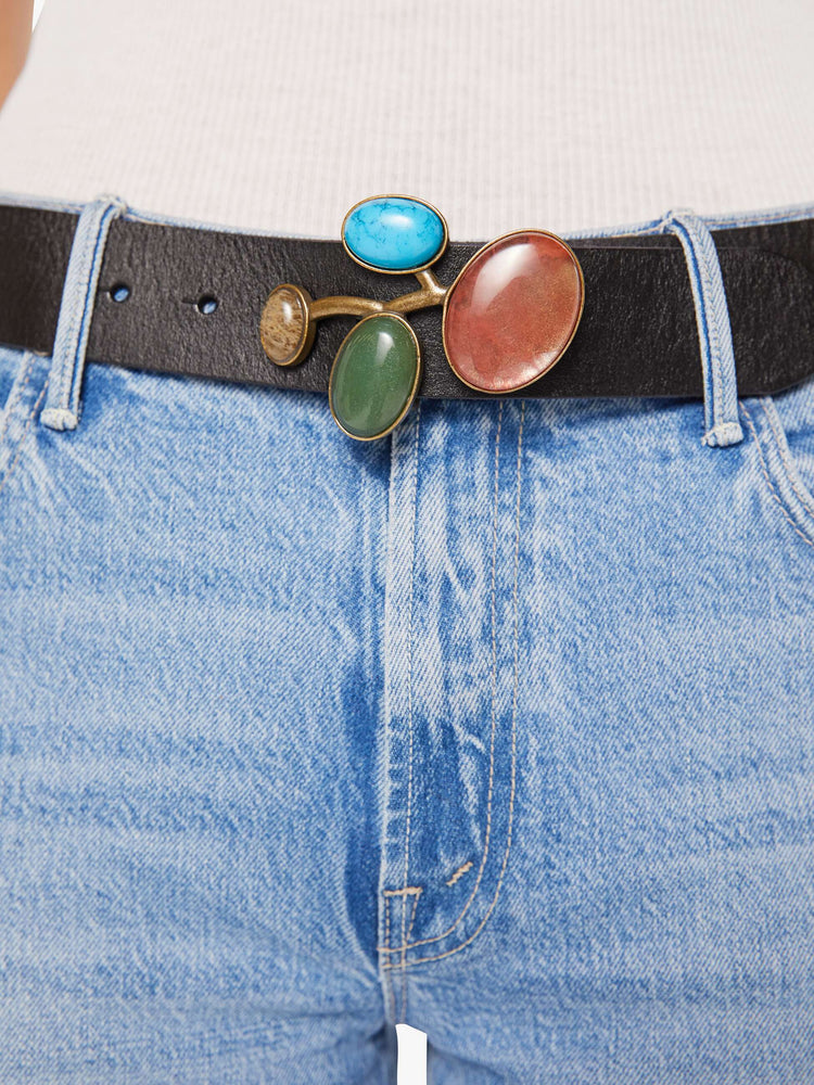 Close up front view of a black leather belt with a chunky metal buckle detailed with turquoise, amber, green and pale yellow stones.