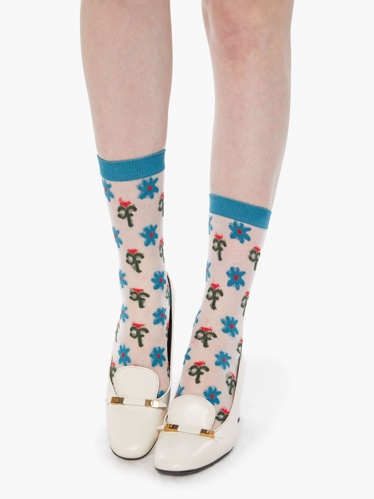 With shoes on model view of an on model in a translucent white fabric with colorful flowers and blue trim.