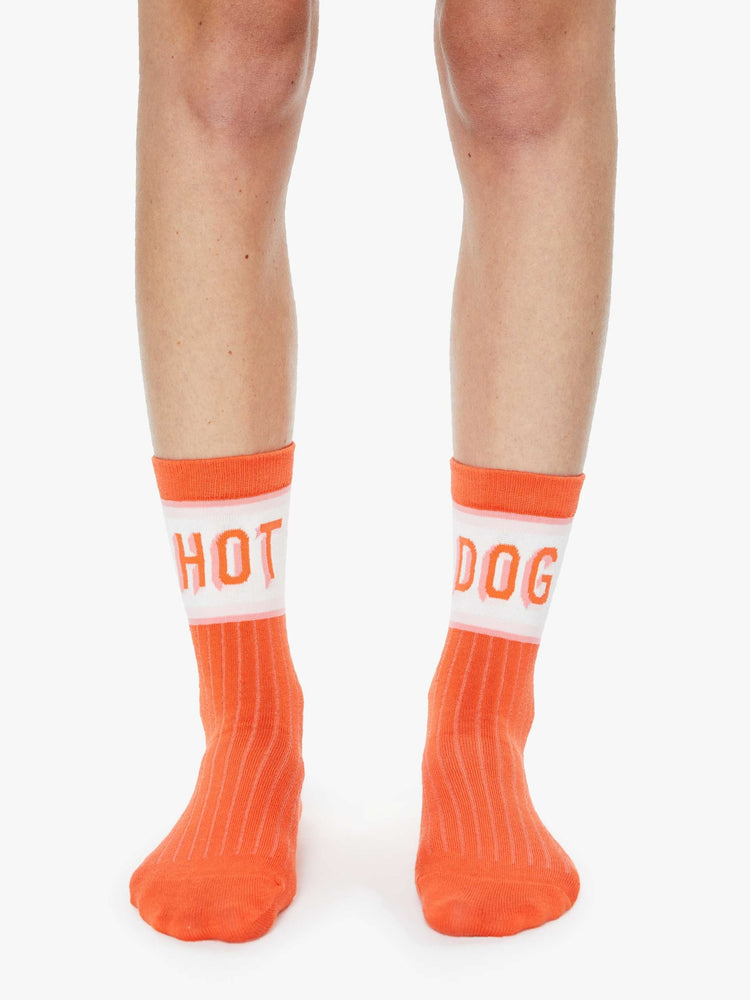 On model view of tube bright orange-red with white and pink stripes and text across the top.