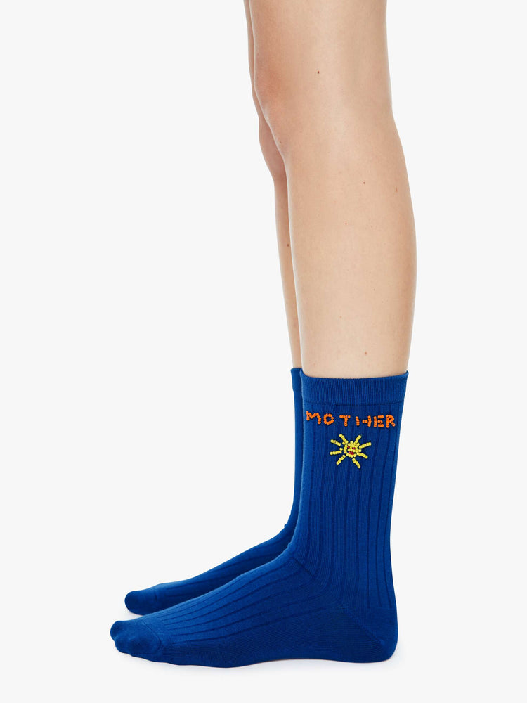 Side on model view of tube socks designed in blue with a sun, red bikini and MOTHER's name beaded on the sides.