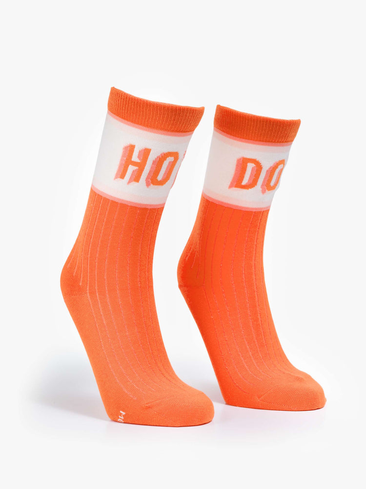 Flat view of tube bright orange-red with white and pink stripes and text across the top.
