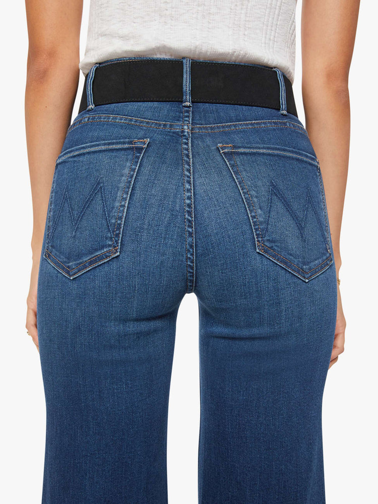 Back view of a wide leather belt designed in black suede with an oversized antique brass buckle detailed with colored gemstones.