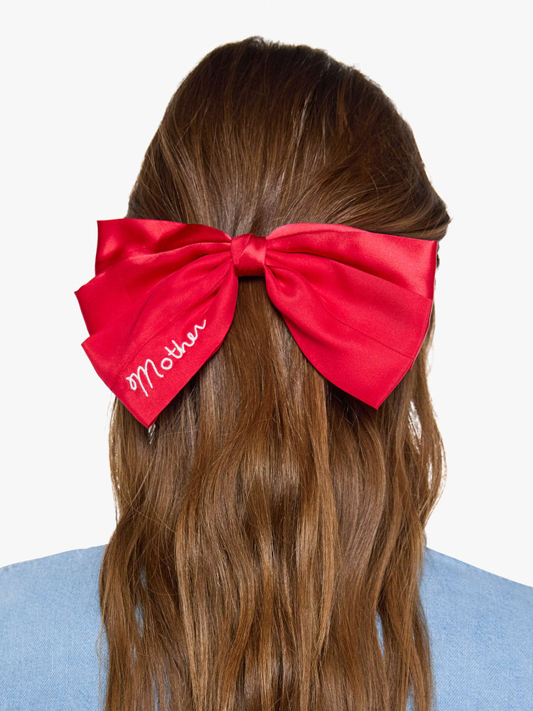 On model view of a woman in a red hair bow that fastens with a metal barrette so you can clip it on.