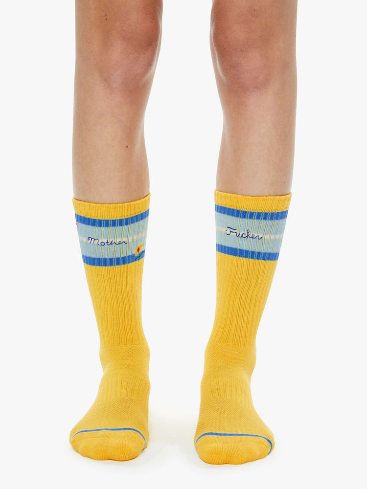 On model view of extra-tall tube socks with an explicit message from MOTHER. Shown here in yellow with blue stripes and text across the top