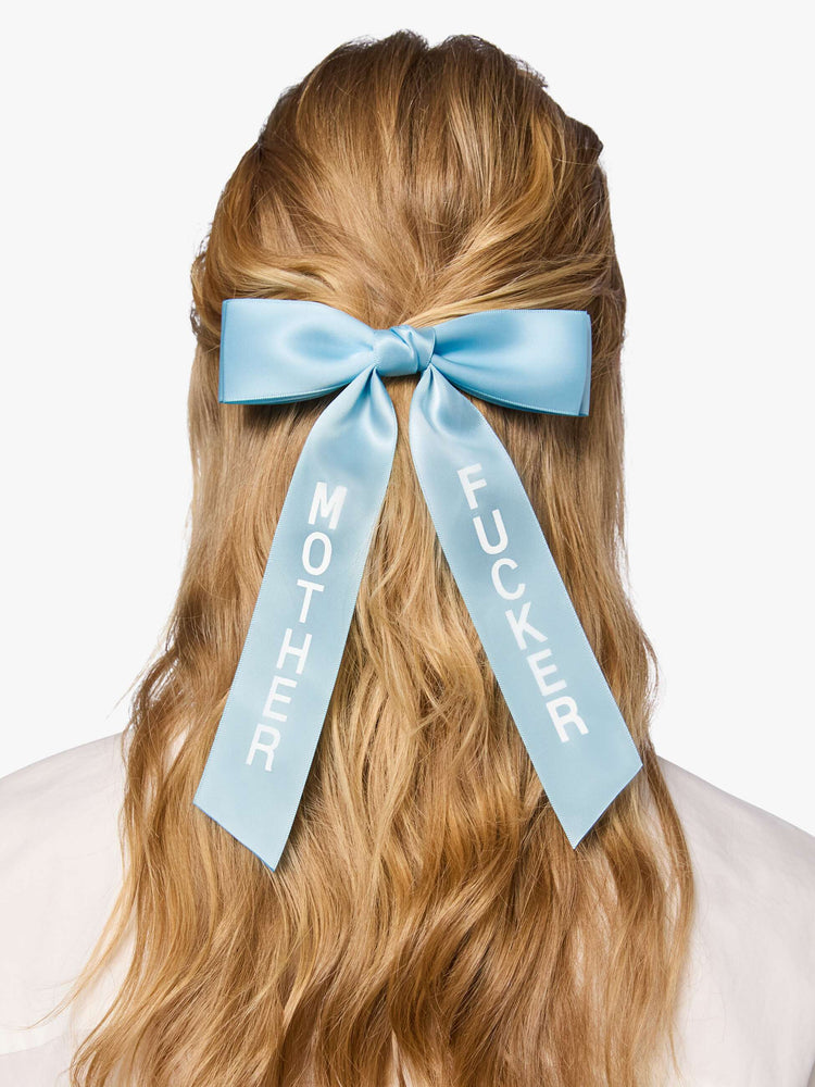 On model Light blue satin-feel hair bow that looks sweet but says otherwise—with MOTHER on one tail and FUCKER on the other.