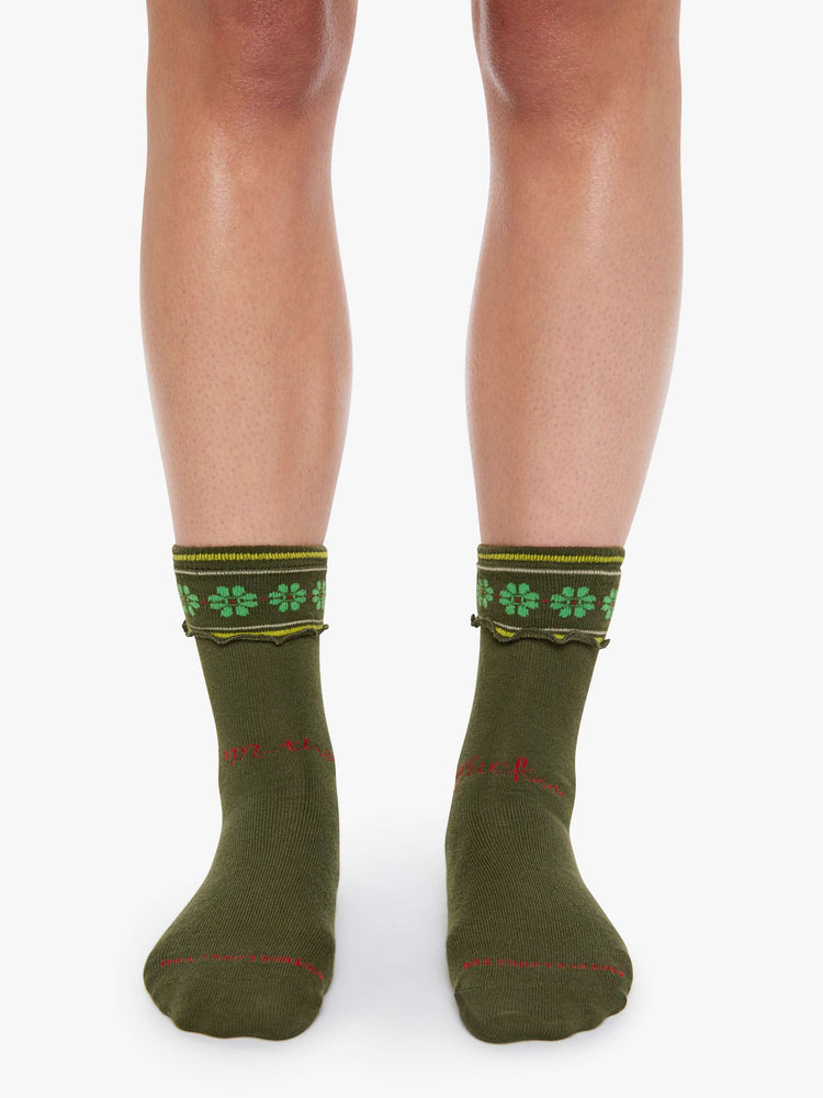 On model view of forest green with lime-green flowers socks with yellow and white stripes and text in red across the front.