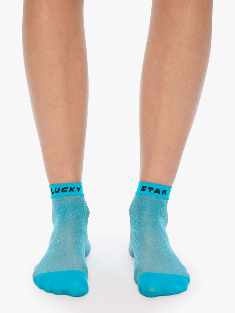 On model view sheer ankle sock designed in glittery turquoise with text in black across the hems.