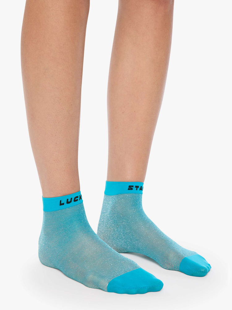 On model view sheer ankle sock designed in glittery turquoise with text in black across the hems.