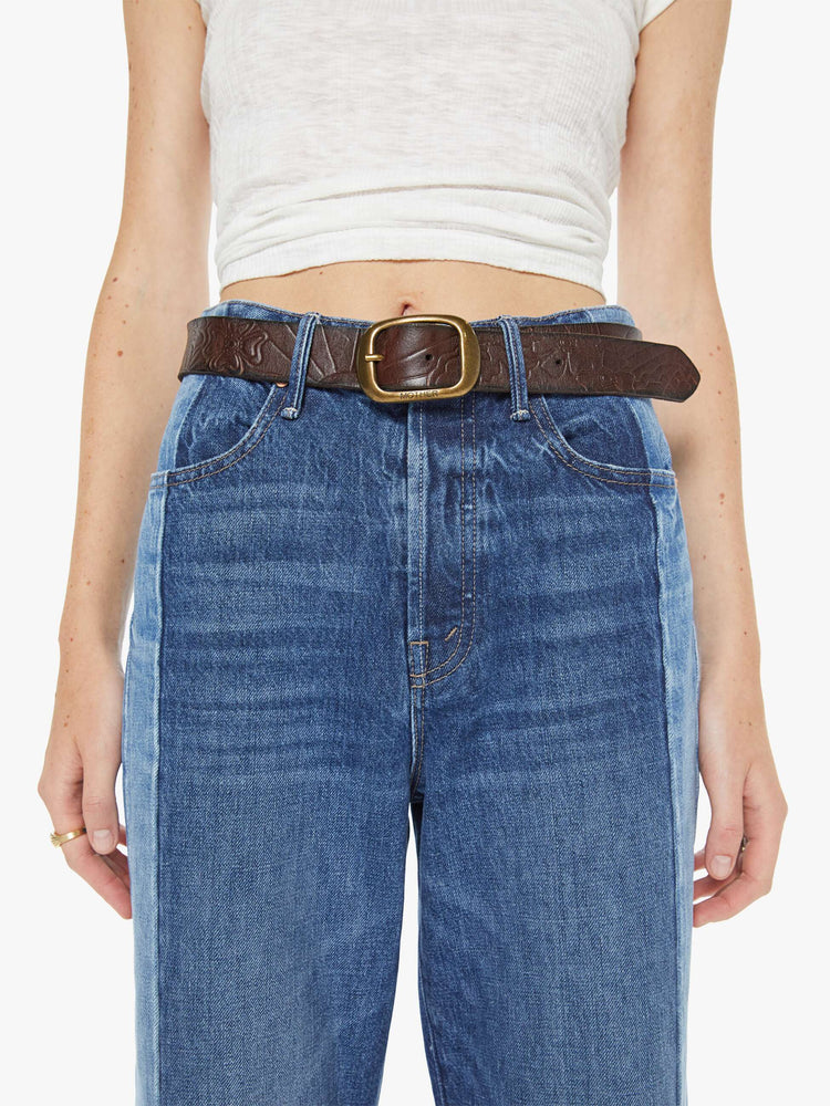 On model  view of a leather belt with an oversized brass buckle.