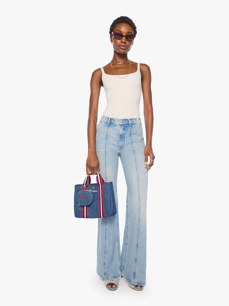 Model view of a woman wearing a classic blue denim with MOTHER embroidered across the front in red, a zip closure and a 1-inch key ring.