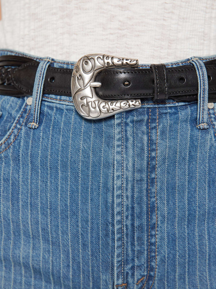 Close up view leather belt with an oversized silver buckle engraved with an explicit message from MOTHER.